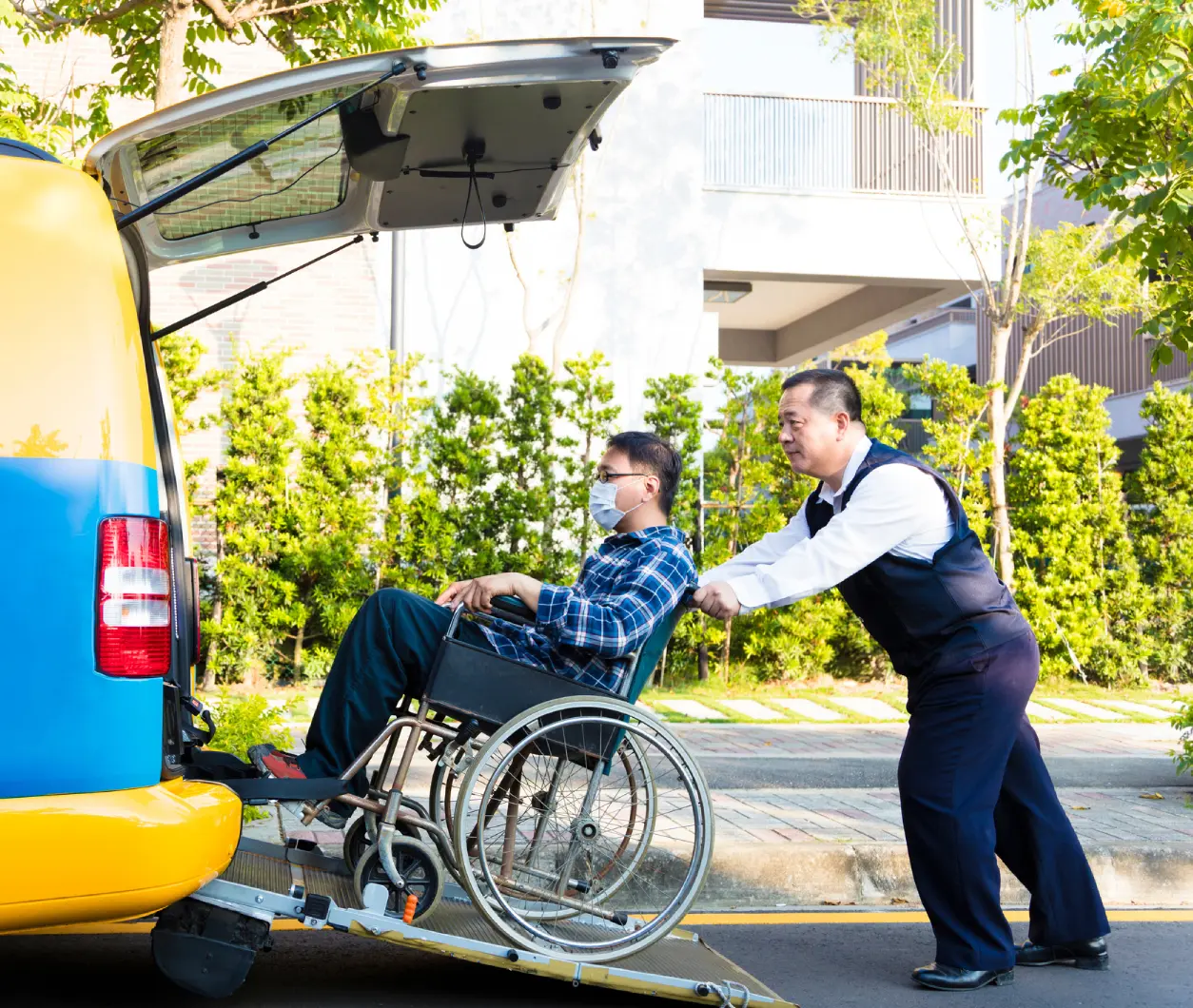 Man assisting wheelchair user into vehicle.