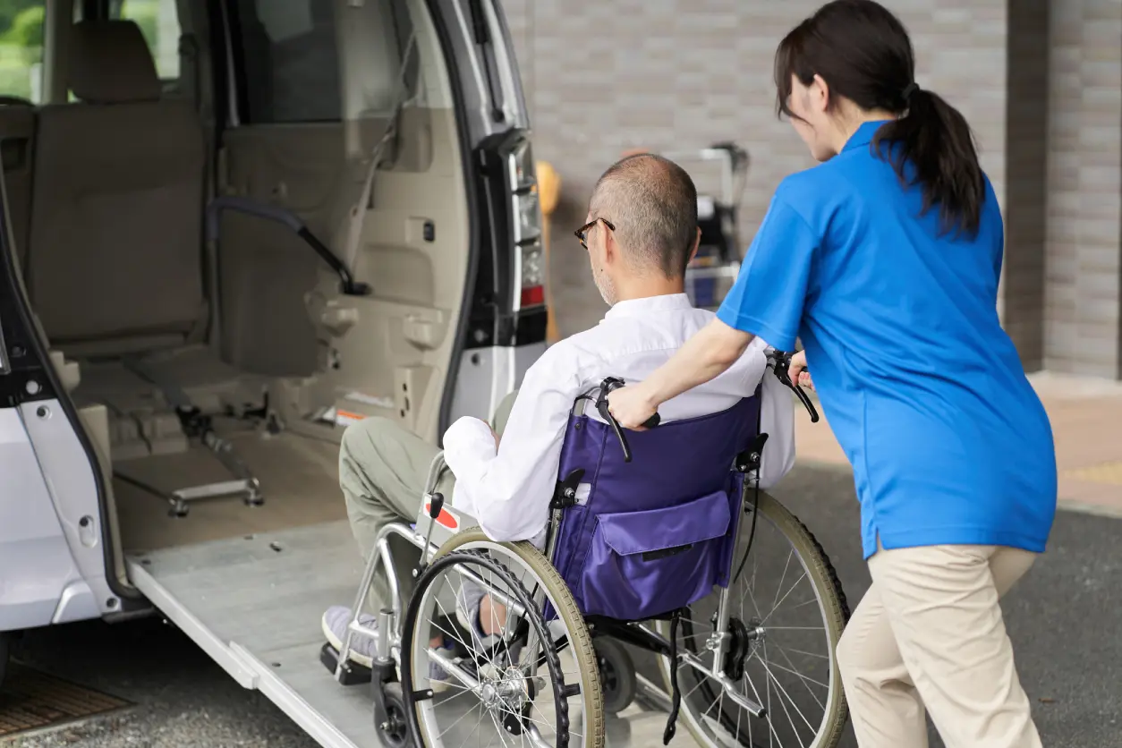 Person assisting wheelchair user into vehicle.